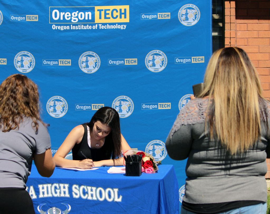 Mazama sophomore Kristalina Derry signs her STEM&M contact while advisor Laura Nickerson, left, and a parent takes photos.